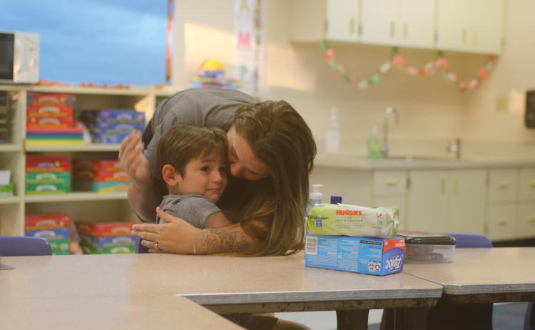 Gunner Statham, 5, a kindergarten student at Five Points Elementary School, flashes a tearful first day of school look as he’s hugged by Gracey Hudson on Monday. (TONY BRITT/Lake City Reporter)
