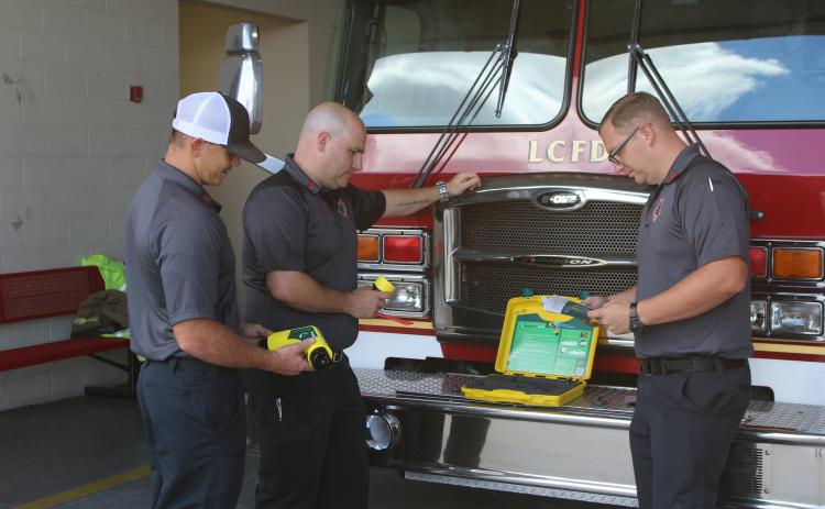 Lake City firefighters Hunter Anderson (from left), Chris Bethea and Gramby Croft look over the department’s new Electric Vehicle Plug Kit and its instruction manual. The newly purchased tool went into service for the department on Monday. (TONY BRITT/Lake City Reporter)