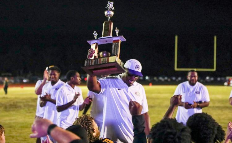 Columbia coach Brian Allen raises the Old Oaken Bucket trophy after his team defeated Suwannee 13-0 on Friday. (BRENT KUYKENDALL/Lake City Reporter)