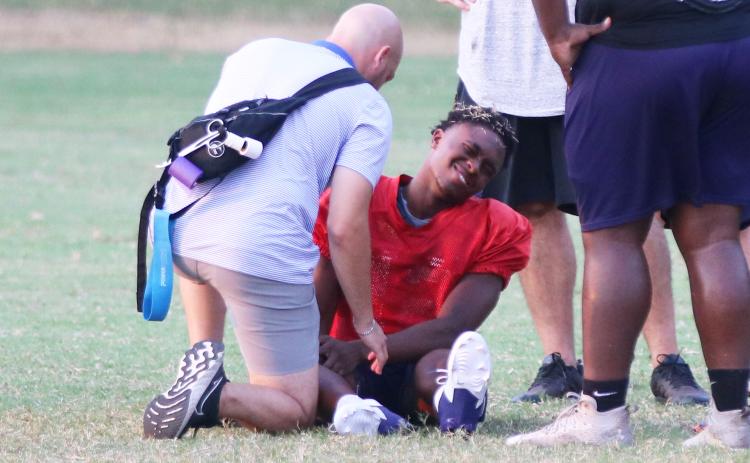Columbia quarterback Xavier Collins has his knee attended to by the team trainer after being injured at the end of Monday’s practice. (JORDAN KROEGER/Lake City Reporter)