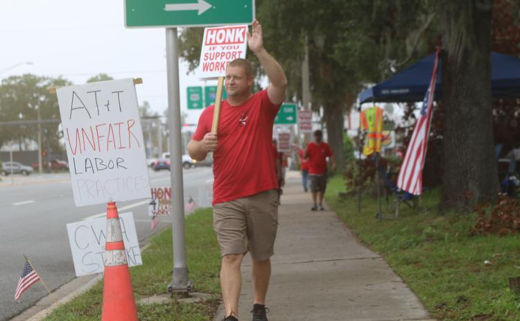 Eric Wilson, an AT&T employee who is on strike, waves at a motorist after the motorist blew their horn for Wilson and the eight other striking employees. (TONY BRITT/Lake City Reporter)