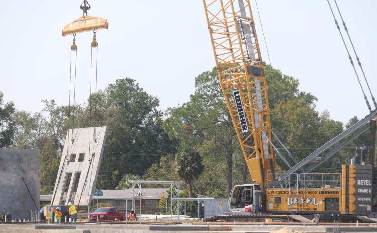 Construction workers help lower a section of one of the walls of the new Niblack Elementary School into position Monday. The walls are being put into place over the next two weeks. (TONY BRITT/Lake City Reporter)