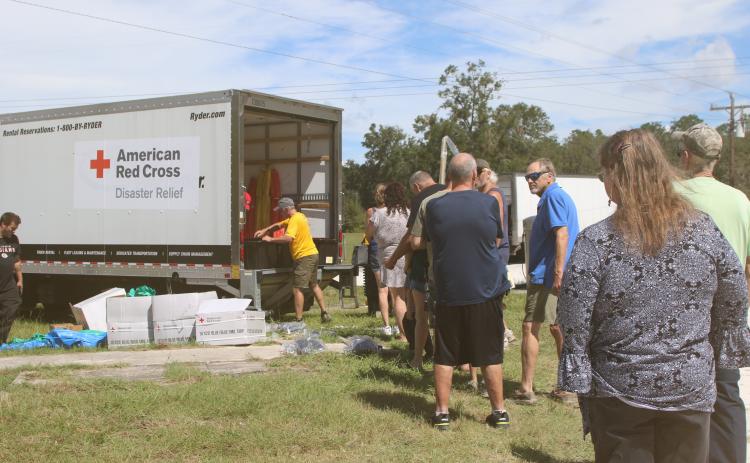 Southern Columbia County residents stand in line to get supplies, including shovels, rakes, tarps, buckets and cleaning supplies, from the American Red Cross in Fort White on Thursday. (TONY BRITT/Lake City Reporter)