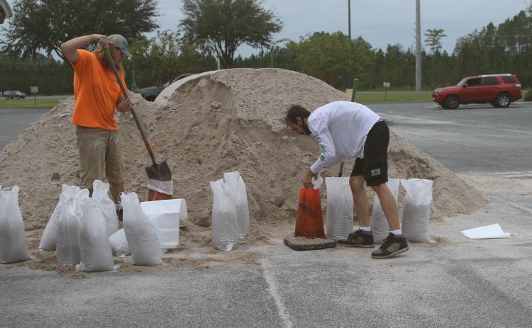 Jasper Webb (from left) and Jonathan Hughes fill sandbags as they prepare for Hurricane Milton. (TONY BRITT/Lake City Reporter)