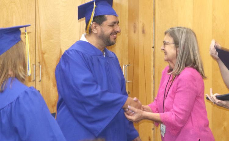 Sergio Miguel Hernandez (from left) is congratulated by Susan Kroh, Columbia County Public Library volunteer and literacy coordinator, as he received his high school diploma in a graduation ceremony on Tuesday night. (TONY BRITT/Lake City Reporter)