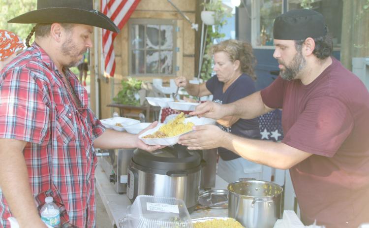 Alexander Veiga, co-owner of The Collective, (right) serves up food during Monday’s event. (TONY BRITT/Lake City Reporter)