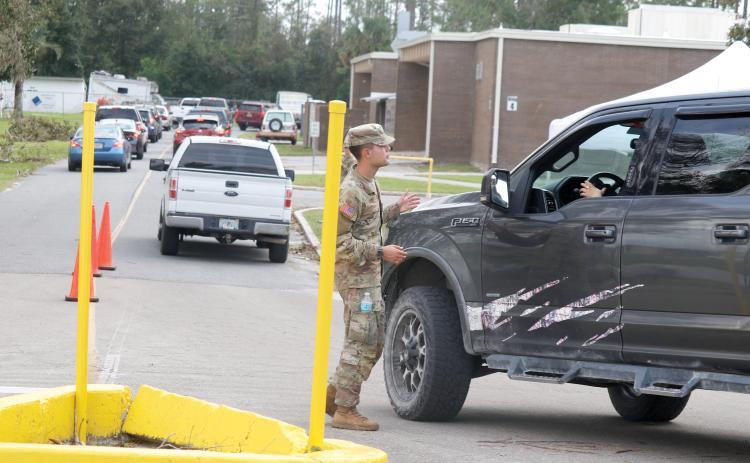 A member of the Florida National Guard helps direct vehicles at a POD (Points of Distribution) site at RIVEROAK Technical College in Live Oak on Saturday. That location has now been moved to the Live Oak Mall at 841 Pinewood Drive SW. (JAMIE WACHTER/Lake City Reporter)