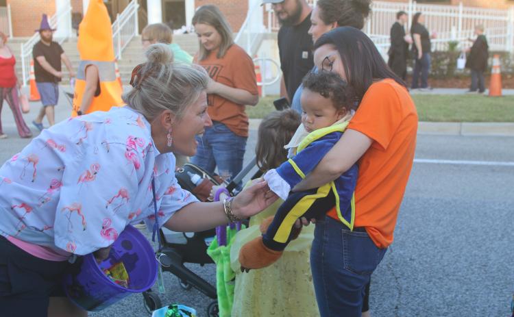 Karri Miles (from left), a DOT employee, interacts with Jaxson Trowell, five months, and his grandmother, Candace Starling, during the DOT’s trunk or treat event on Thursday night. (TONY BRITT/Lake City Reporter)