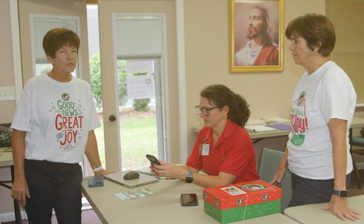 Beth Bullard (from left), Cheri Schultz and Lou Blanton, volunteers at the Operation Christmas Child Shoebox Collection Center in Lake City, work with other volunteers to collect and ship the shoeboxes to Atlanta. (TONY BRITT/Lake City Reporter)