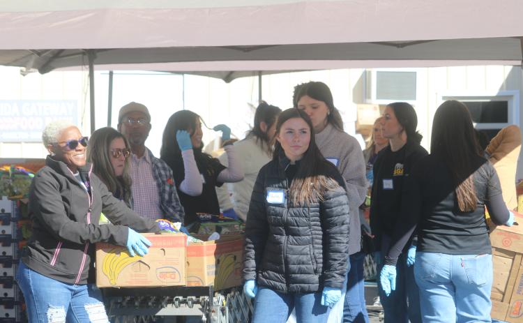 Xavier White (left) and Taylor Carroll wait for a client from Catholic Charities to park their vehicle so they can unload boxes of food into the car. Catholic Charities served approximately 650 people during this year’s Thanksgiving food distribution. (TONY BRITT/Lake City Reporter)