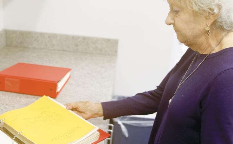Mary Loughran, the daughter of Mary Ethel Anderson, looks through a binder containing some of the ‘Goodie Books’ that her mother created as a county extension service agent. (TONY BRITT/Lake City Reporter)
