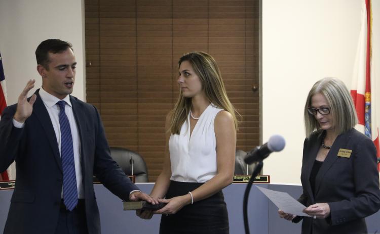 Lake City Mayor Noah Walker takes the oath of office Monday at the outset of the Lake City Council meeting as his wife, Chani, looks on while holding the Bible that he took the oath on. (MORGAN MCMULLEN/Lake City Reporter)