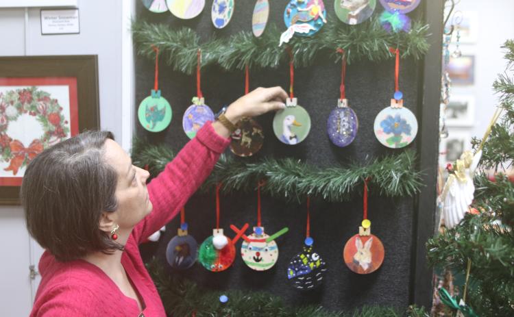 Sheila Carr, Gateway Art Gallery curator, organizes a display of Christmas decorations that are for sale during the organization’s annual Mistletoe Magic fundraiser. (TONY BRITT/Lake City Reporter)