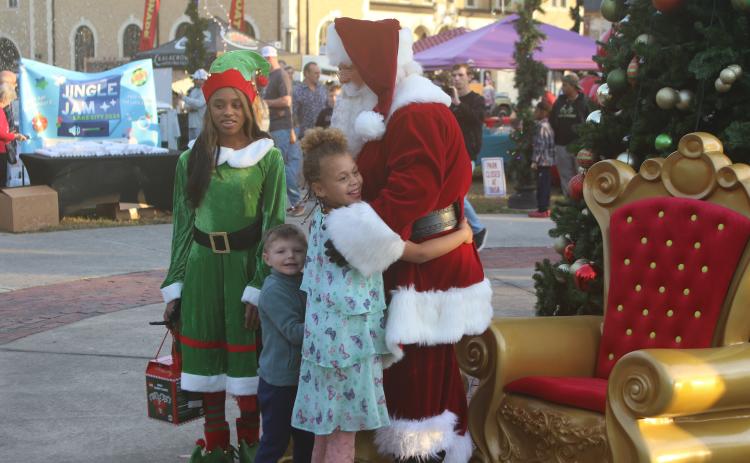 Santa Claus and one of his elves welcome a pair of children at the Christmas tree lighting  ceremony at Olustee Park Sunday night. (TONY BRITT/Lake City Reporter)