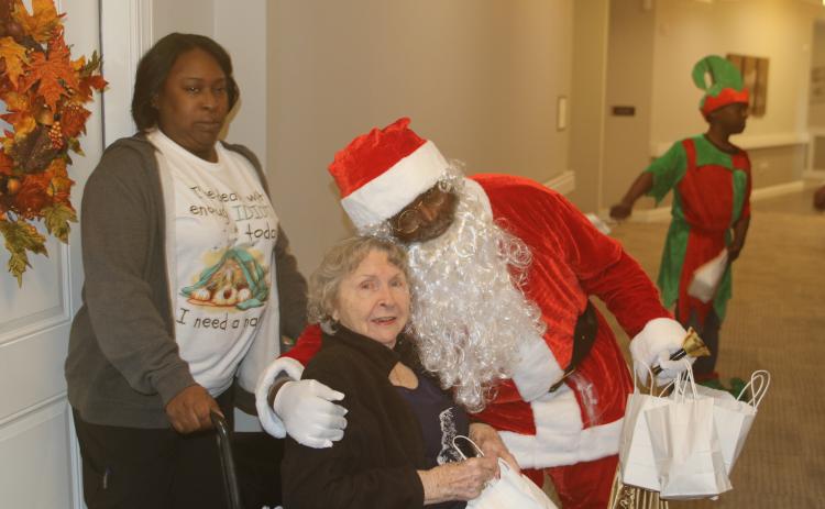 Trudie Johns gets a hug from Joseph Simmons, who portrayed Santa Claus on Sunday afternoon when members of the Our Community Cares Coalition visited residents at The Canopy at Harper Lake. (TONY BRITT/Lake City Reporter)