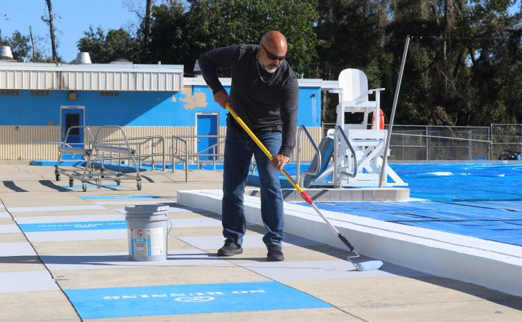 Chris Cuadras, the new aquatic director for the Columbia County School District, applies some Cool Deck paint to the concrete around the pool Monday. (JAMIE WACHTER/Lake City Reporter)