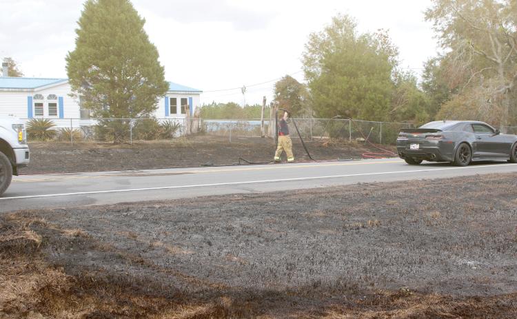 A Columbia County firefighter extends a hose as firefighters and law enforcement officers battled a brush fire Saturday afternoon on State Road 47 that jumped the road and threatened a home. (TONY BRITT/Lake City Reporter)