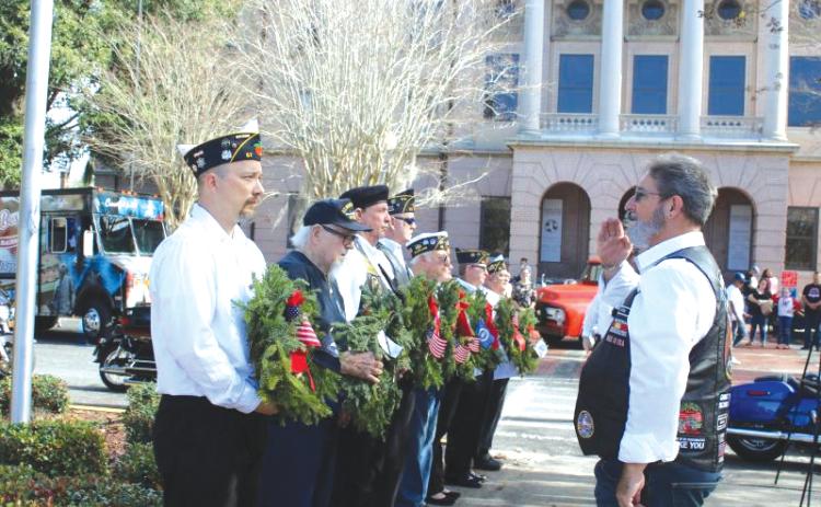 Mike Ziegler (left) holds a wreath for the POW/MIA memorial as he is saluted by Robert Mixon during the local Wreaths Across America event in 2022. (FILE)