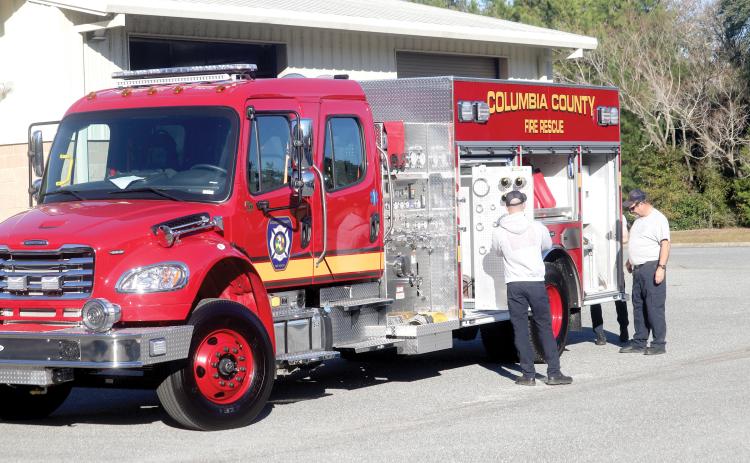 Columbia County Fire Rescue driver/engineer Lucas Harrell (from left) adds firefighting equipment to a new department truck as Columbia County Fire Rescue Battalion Chief Arness Thomas overlooks the operation. Columbia County Fire Rescue could have three new trucks on the department’s front lines by the end of April. (TONY BRITT/Lake City Reporter)
