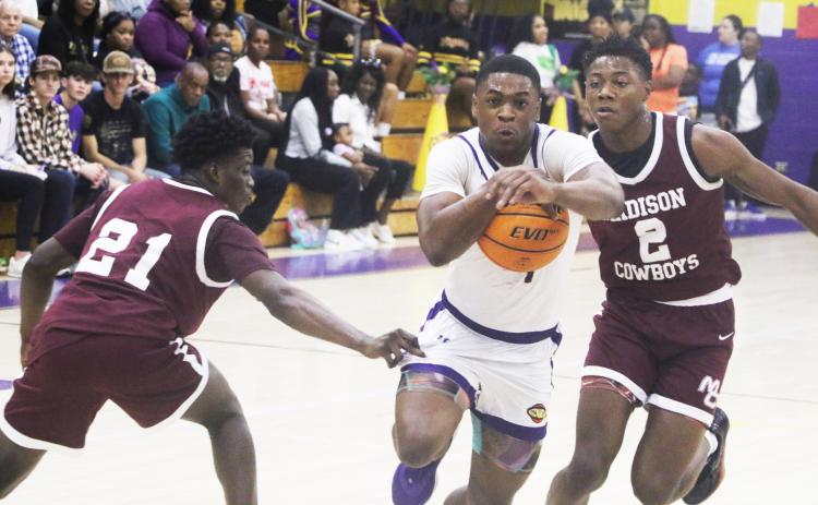 Columbia guard Zamarion Jones drive to the basket between Madison County’s Sean Williams (21) and Jhy Smith (2) on Friday night. (MORGAN MCMULLEN/Lake City Reporter)