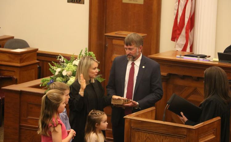 Kathryn ‘Katy’ Land is sworn in as a Third Judicial Circuit judge Friday by Judge Melissa Olin as her husband, Travis, holds the Bible. They are joined by their children Jack, Dylan and Tyler. (MORGAN MCMULLEN/Lake City Reporter)