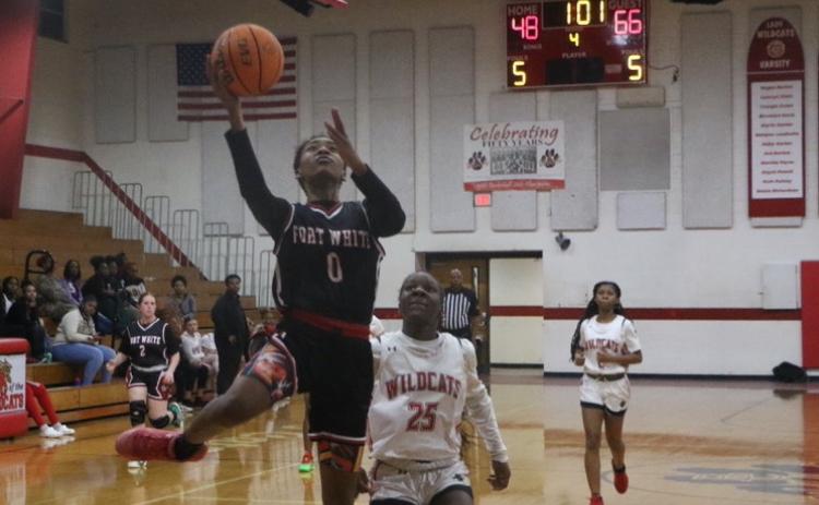Fort White guard Isreal Hart goes for a layup past Baker County’s Kaitlyn Holland late in the fourth quarter of Tuesday’s win. (MORGAN MCMULLEN/Lake City Reporter)
