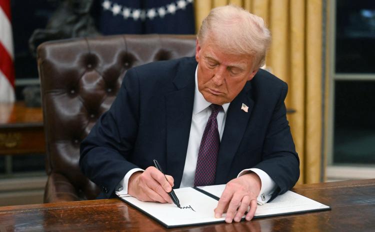 President Donald Trump signs an executive order in the Oval Office at the White House on Monday. One of the executive orders Trump signed either commuted the sentences or pardoned those involved with the Jan. 6, 2021, events at the Capitol. (JIM WATSON/AFP/Getty Images/TNS)