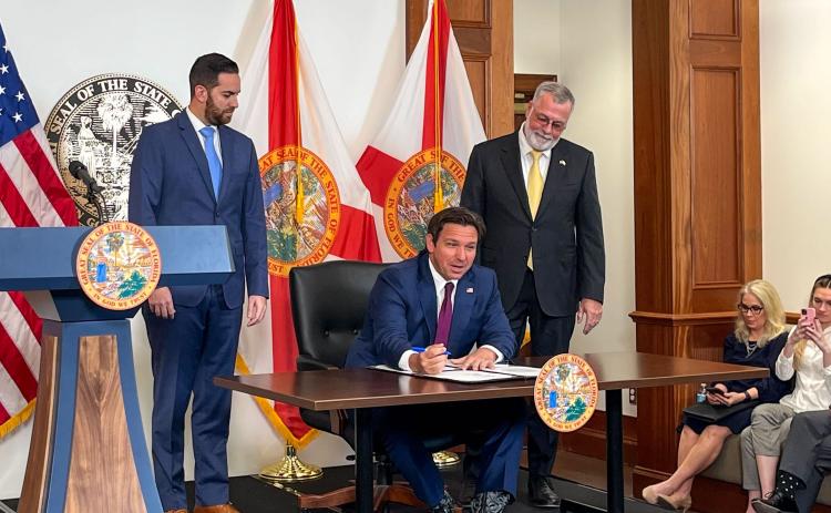 Florida House Speaker Daniel Perez and Senate President Ben Albritton watch Gov. Ron DeSantis sign legislation to address illegal immigration on Thursday. (LAWRENCE MOWER/Miami Herald/TNS)