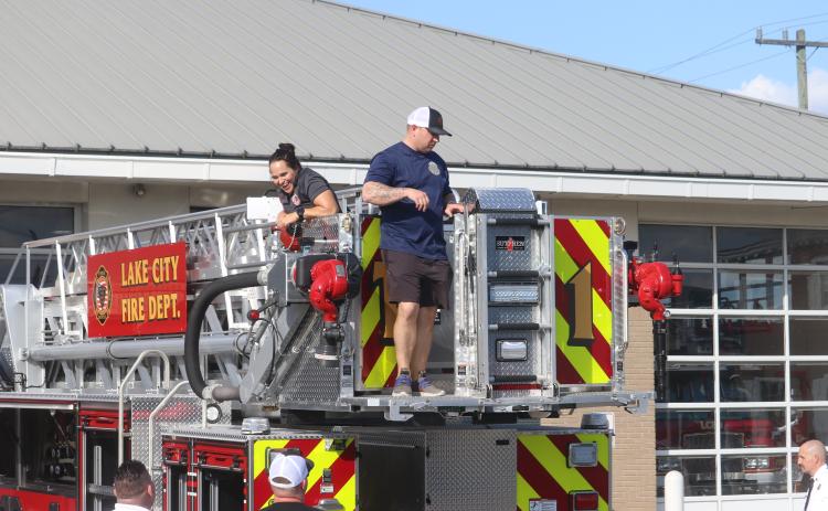 Lake City firefighter Christina Munro (left) flashes a big grin as she and Dustin Alford look over the fire department’s newest engine on Thursday. (TONY BRITT/Lake City Reporter)