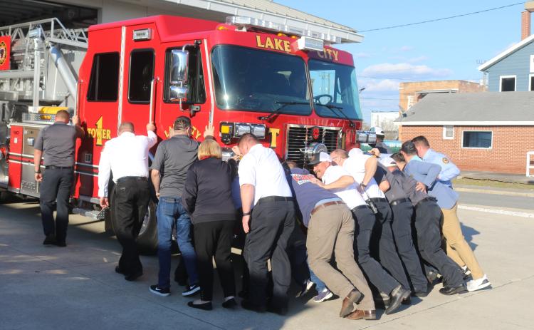 Members of the Lake City Fire Department push the department’s new tower truck into the Lake City Public Safety Building on Tuesday. The push-in ceremony is a traditional way to put new vehicles into service. (TONY BRITT/Lake City Reporter)