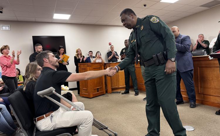 Suwannee County Deputy Justin Dalton, shot and injured in a chase of a murder suspect Friday morning, shakes hands with Gadsden County Sheriff Morris Young. Young and Suwannee County legislators, Sen. Corey Simon and Rep. Jason Shoaf, honored Dalton on Monday with a state flag that flew over the Florida Capitol on Friday. (JAMIE WACHTER/Lake City Reporter)