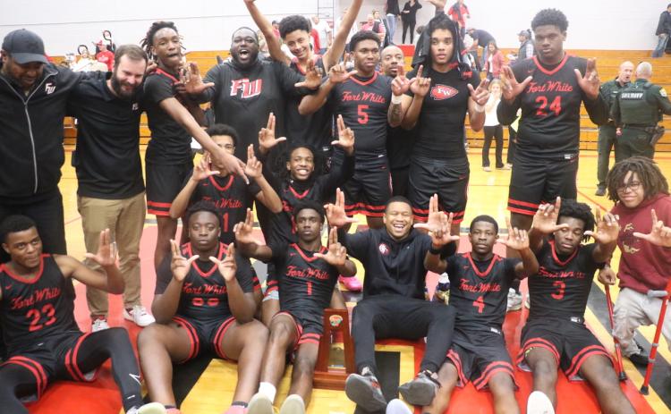 Fort White’s boys basketball players and coaches hold up their Ls after earning a trip to Lakeland with a 54-51 win over Hilliard in the Region 3-R championship on Tuesday. (MORGAN MCMULLEN/Lake City Reporter)