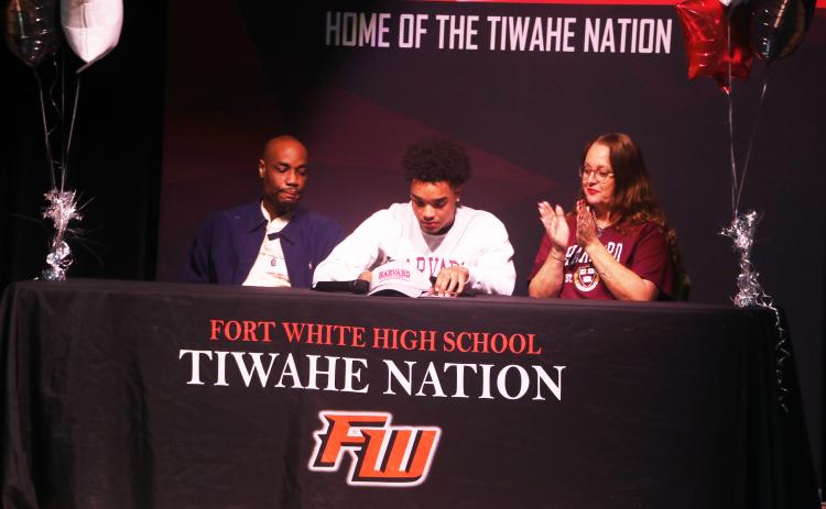 Fort White receiver Tafari Moe (center) signs his letter of intent to play football at Harvard University on Wednesday morning flanked by his parents, Russel (left) and Loretta (right). (MORGAN MCMULLEN/Lake City Reporter)