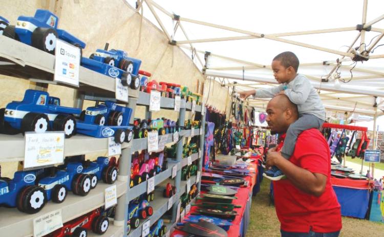 Keaven Jones gives Kaden Jones a ride on his shoulders as the youngster points out wooden cars in a vendor’s booth at last year’s Olustee Festival. (FILE)