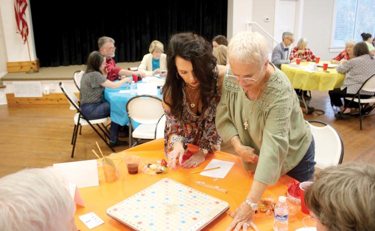 Patti Kahlich (left) and her Scrabble partner Rene Keith, stand up to get a better vantage point while competing in last year’s Scrabble Tournament at the Club House on Lake Isabella. (FILE)