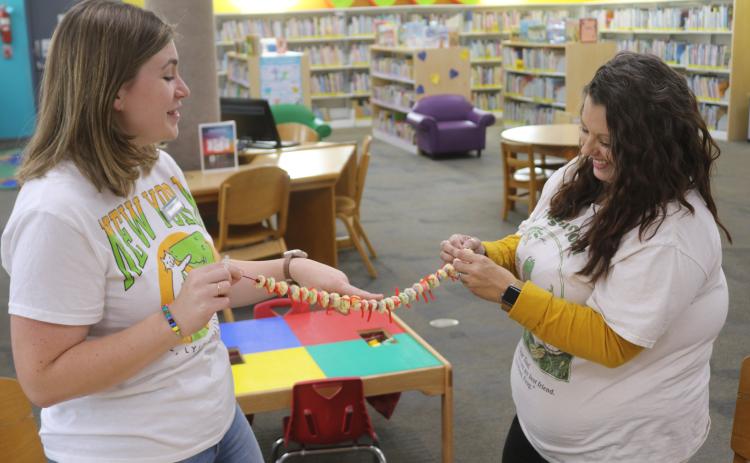 Kate Duong (from left), Columbia County Public Library assistant director, and Andrea Sirard, Columbia County Youth Services librarian, work on creating an edible spinal column made of cereal and candy. (TONY BRITT/Lake City Reporter)