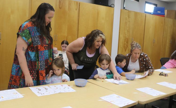 Alexa DeMarco (standing left) and Tracy Lock (standing right) help Cyrilla Matthews, 4, and Atlas Matthews, 5, during the workshop. (TONY BRITT/Lake City Reporter)