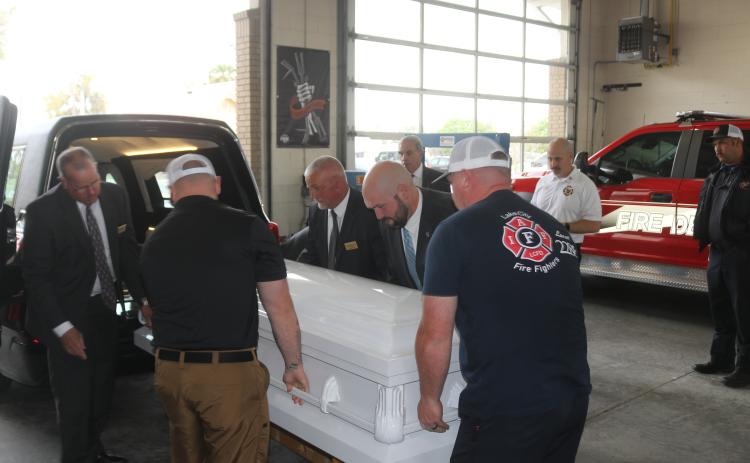 Lake City firefighters and members of Gateway-Forest Lawn Funeral Home pull a casket out of a hearse that the funeral home is donating to the department for training with the honor guard. (TONY BRITT/Lake City Reporter)