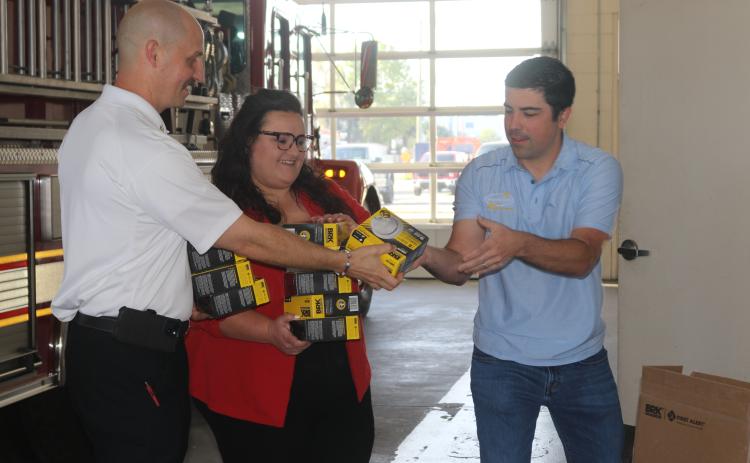 Joseph Peurrung, the owner of Security Safe (right), and Chelsea Flores, owner of Chelsea Flores State Farm Insurance, donated 24 smoke detectors to the Lake City Fire Department this week. Assistant Fire Chief Ret Tompkins accepted their donation. (TONY BRITT/Lake City Reporter)