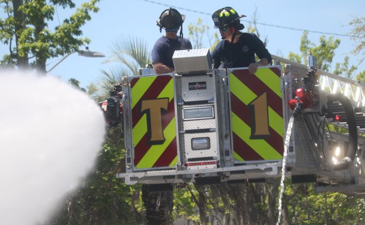 Lake City firefighters Hunter Anderson (from left) and Elliot Redish use two different hoses that will be used to douse blazes as they trained in the department’s newest fire truck. (TONY BRITT/Lake City Reporter)