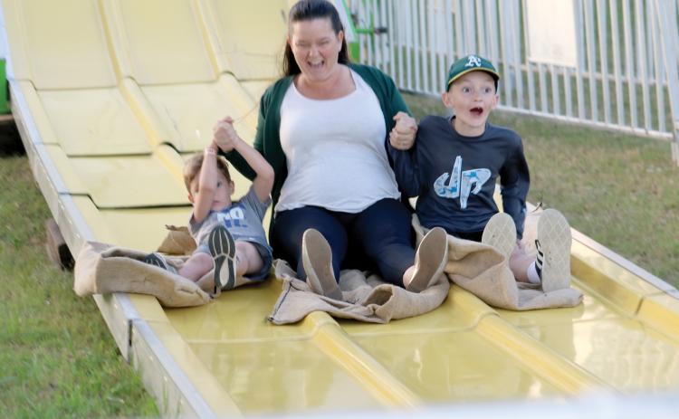 A woman and a pair of children enjoy their trip down a slide at a previous year’s Suwannee County Fair, which opens Friday and runs for nine days. (FILE)
