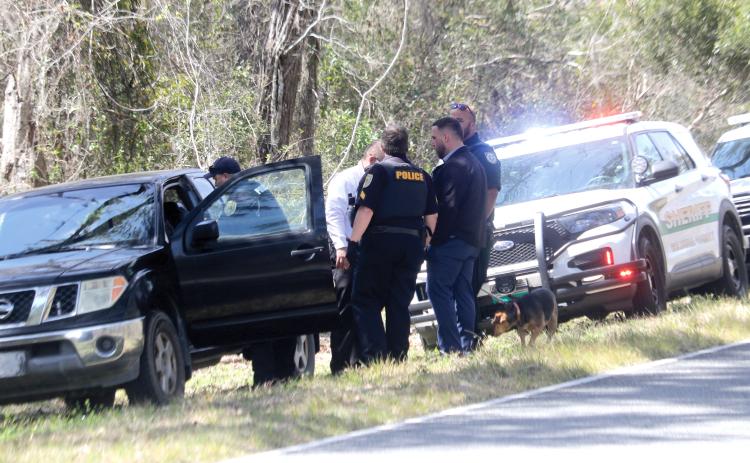 Lake City police officers talk after a black Nissan Frontier pickup was pulled over Monday afternoon on County Road 252. The driver of the pickup, Joe Markham, was arrested for pulling a firearm during a road rage incident moments before on S. Main Boulevard. (TONY BRITT/Lake City Reporter)