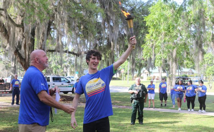 Columbia County Sheriff’s Office Sgt. Clint Dicks (left) looks on as Wyatt Kelly, of Lake City Christian Academy, proudly displays the torch moments before the annual Law Enforcement Torch Run for Special Olympics Florida on Tuesday morning. (TONY BRITT/Lake City Reporter)