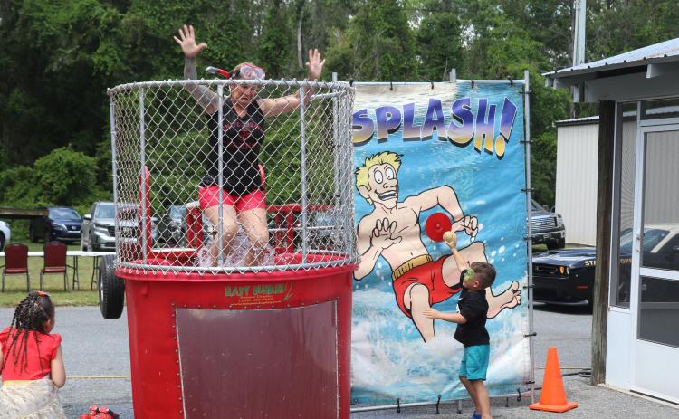 Seven Blumer falls in the water of the dunk tank on Saturday as an child presses the release mechanism. (TONY BRITT/Lake City Reporter)