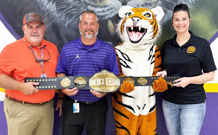 Columbia High Principal Trey Hosford (second from left), the school’s mascot and Student Government Director Tia Gainey accept the Florida Department of Transportation District 2 Battle of the Belts championship belt. (COURTESY)