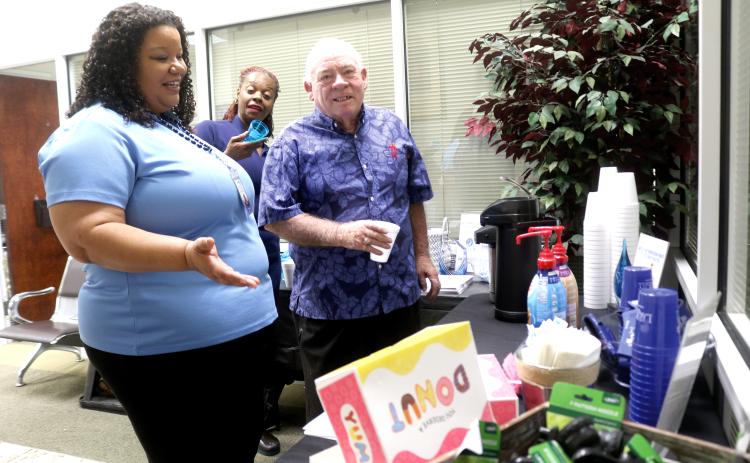 Chanel Neff (clockwise from left), a City of Lake City Customer Service Department employee, encourages Tequela Donaldson and Carroll Lee to get some donuts and coffee during the city’s customer service appreciation festivities last Friday. (TONY BRITT/Lake City Reporter)