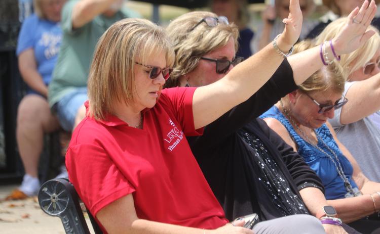 BillieJo Bible (from left), Donna Reese, Sue Tuell and Janet O’Connell raise their hands as they pray in Olustee Park during the National Day of Prayer event on Thursday afternoon. (TONY BRITT/Lake City Reporter)