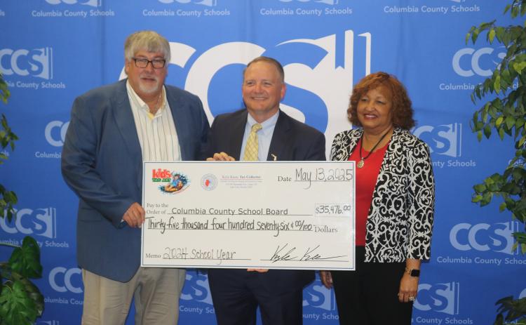 Columbia County Tax Collector Kyle Keen (middle) presents a $35,476 check to Superintendent Keith Couey and School Board Chair Narrie Smith as the proceeds from the Kids Tag Art program. (TONY BRITT/Lake City Reporter)