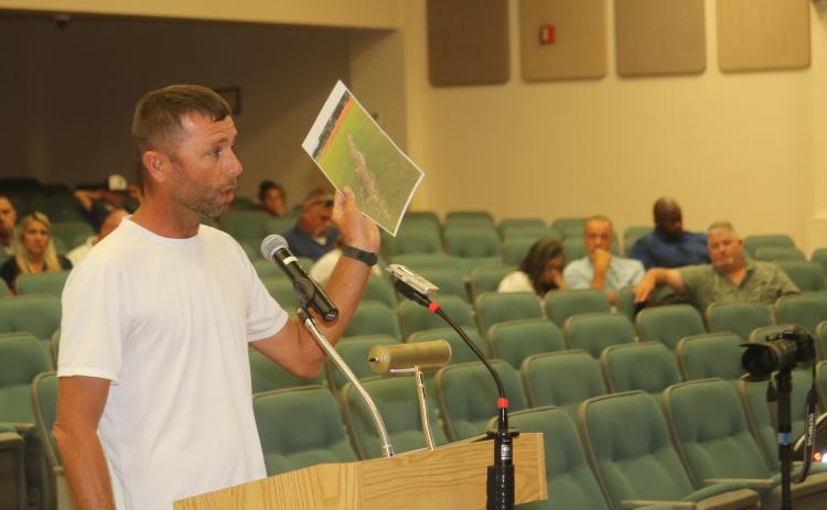 Bobby Griffis shows county commissioners a picture of damage to a local field during Thursday evening’s county commission meeting as several citizens attended the meeting opposing the plan to raise field usage fees for travel ball teams. (TONY BRITT/Lake City Reporter)
