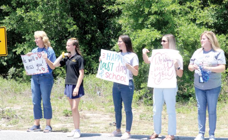 Eastside Elementary School faculty and staff members stand along SE Beech Street on Friday afternoon with signs, as students head home for summer vacation. Eastside Elementary School completed its last day of classes on Friday in the building that was opened in 1959. The building will will be demolished in a few weeks, making way for a new Eastside Elementary School. (TONY BRITT/Lake City Reporter)
